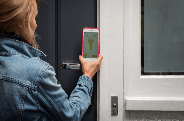 Seorang wanita membuka kunci pintu melalui ponsel dengan YaleTM Conexis L1 Smart Door Lock